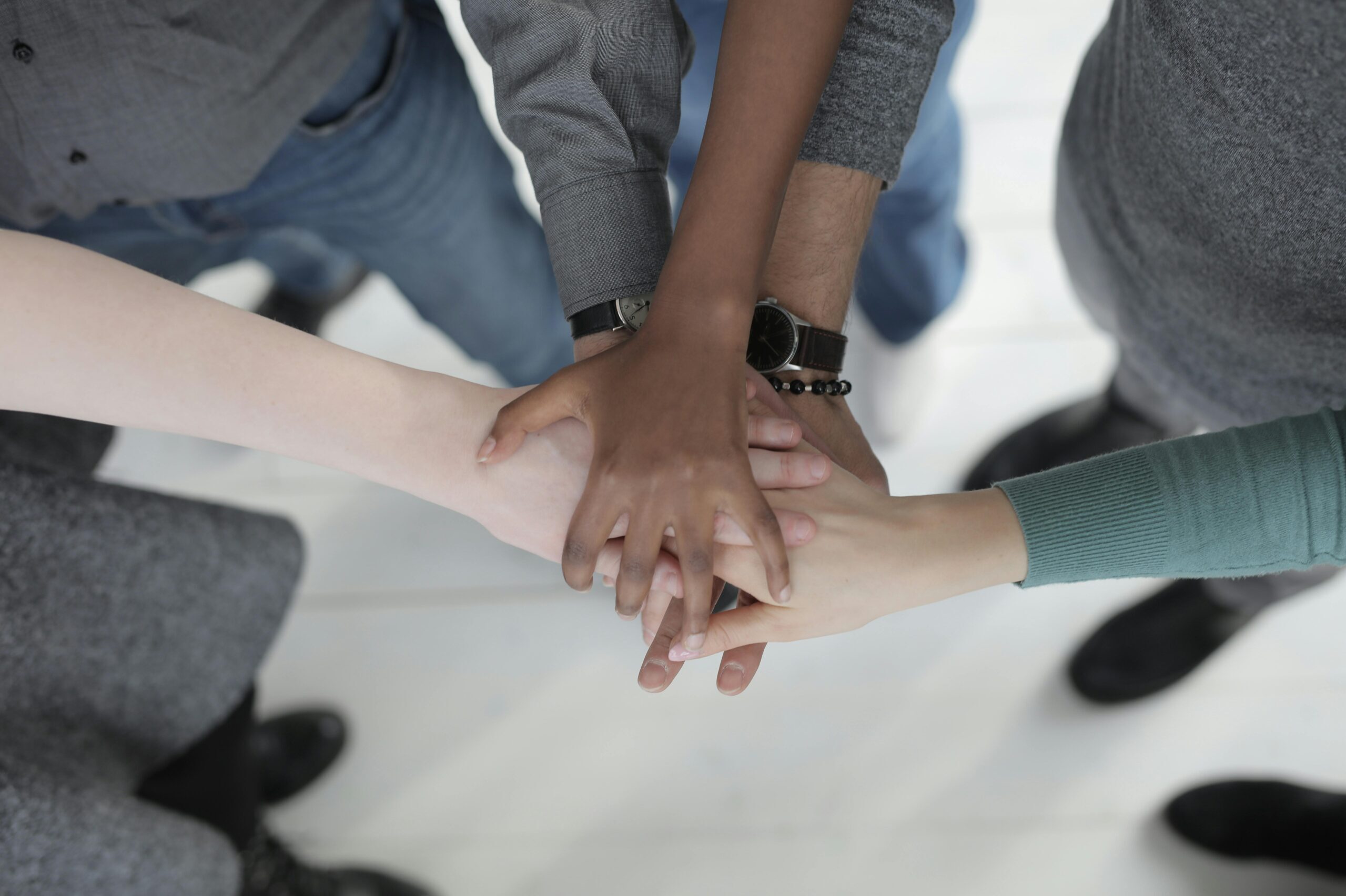 A close-up of diverse hands holding each other in a supportive and unified gesture.